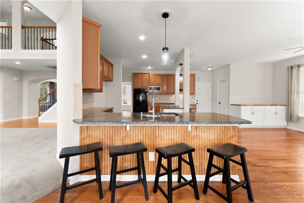 1070 Coleridge Way Suwanee, GA 30024 - Photo 16 of 76 a kitchen with stainless steel appliances kitchen island granite countertop a dining table chairs and white cabinets