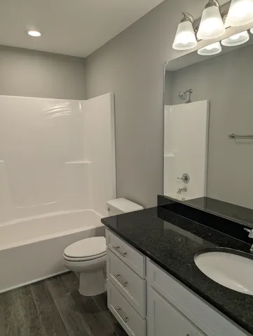 a bathroom with a granite countertop sink a toilet a mirror and bathtub