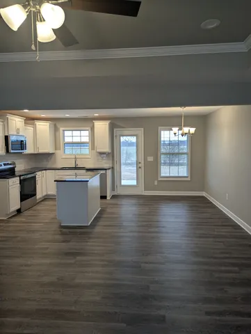 a view of a kitchen with kitchen island a sink wooden floor and a large window