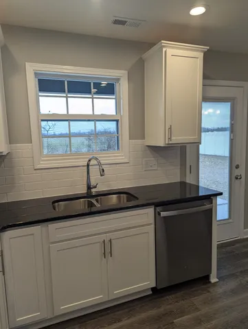 a kitchen with granite countertop white cabinets and a black umbrella