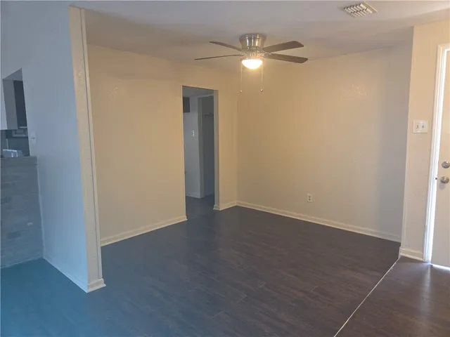 an empty room with wooden floor fan and window