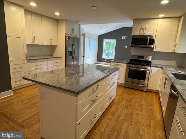 a kitchen with kitchen island granite countertop a stove and a sink
