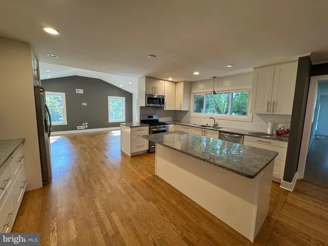a large kitchen with granite countertop a large counter top stainless steel appliances and cabinets