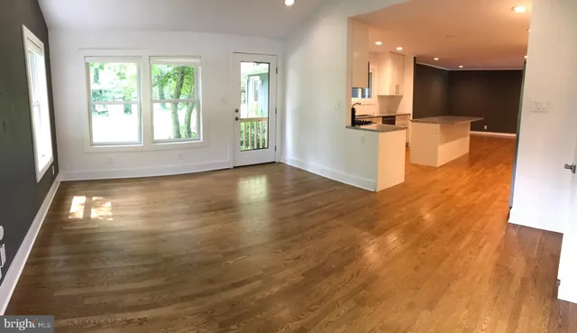 a view of a kitchen with kitchen island a sink wooden floor and a large window