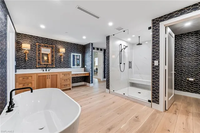 a bathroom with a tub a sink a mirror and shower