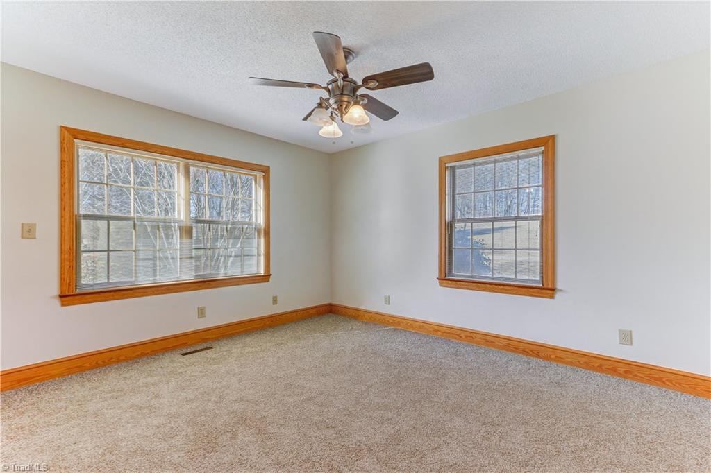 761 Hudson Road Summerfield, NC 27358 - Photo 15 of 28 Bedroom 2 has wall to wall carpeting and ceiling fan with light fixture. Two large windows bring in ample natural light.