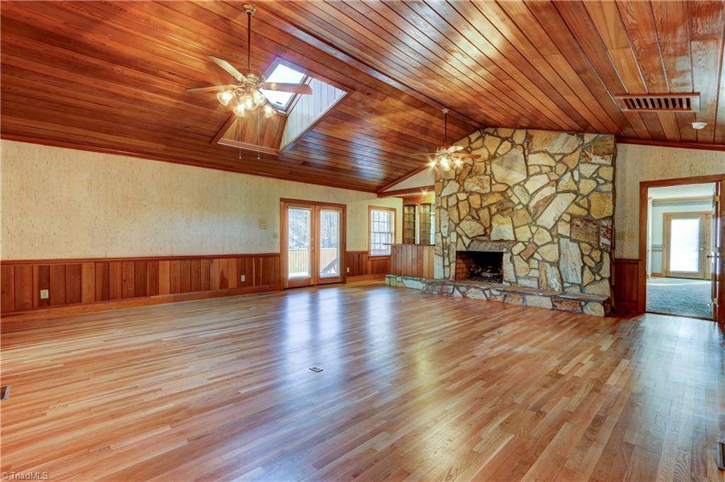 761 Hudson Road Summerfield, NC 27358 - Photo 3 of 28 The Great Room has vaulted ceilings, ceiling fan, sky light, and hardwood flooring. Stone floor to ceiling fireplace with gas logs and stone hearth. Tongue and Groove wood ceiling and wainscoting.
