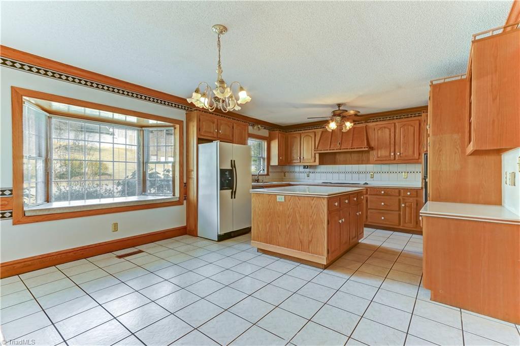 761 Hudson Road Summerfield, NC 27358 - Photo 7 of 28 The Breakfast Room has a central chandelier, tile floor, bay window/window seat and wood molding details.