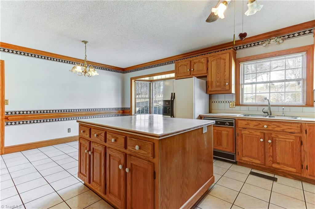 761 Hudson Road Summerfield, NC 27358 - Photo 9 of 28 Another view of the kitchen showing the center island, double sink, and dishwasher. Kitchen has easy care tile flooring.