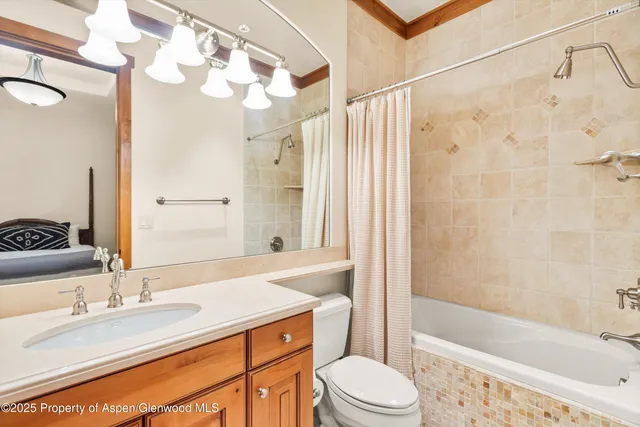 a bathroom with a granite countertop sink toilet a mirror a bathtub and shower