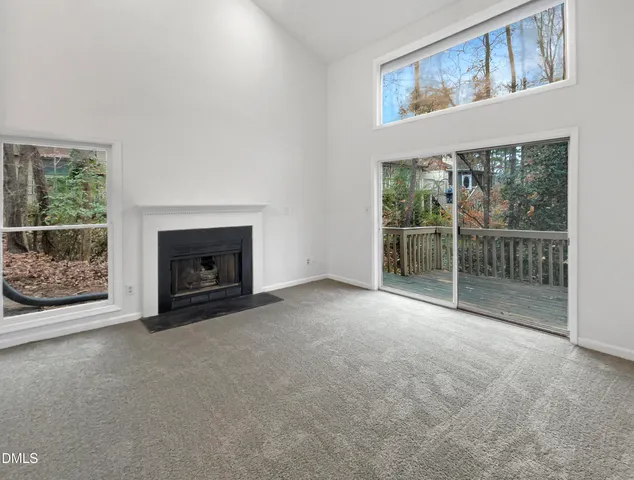 a view of empty room with floor to ceiling window and fireplace