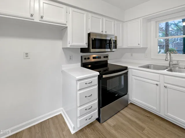 a kitchen with white cabinets stainless steel appliances and sink