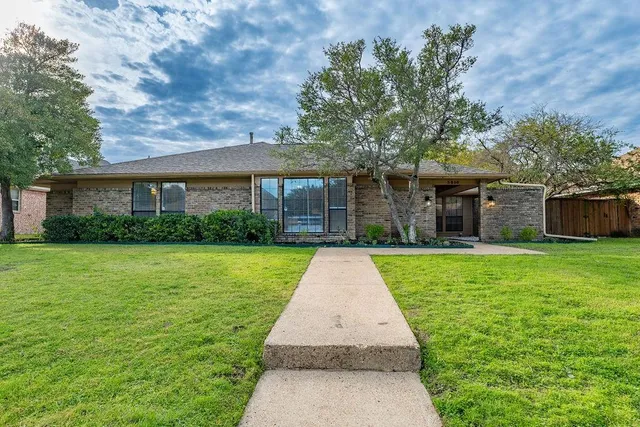a front view of a house with a yard and potted plants