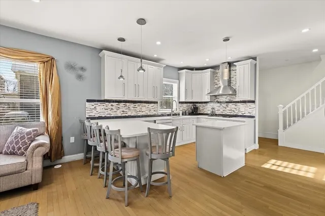 a kitchen with kitchen island granite countertop wooden floors and white stainless steel appliances