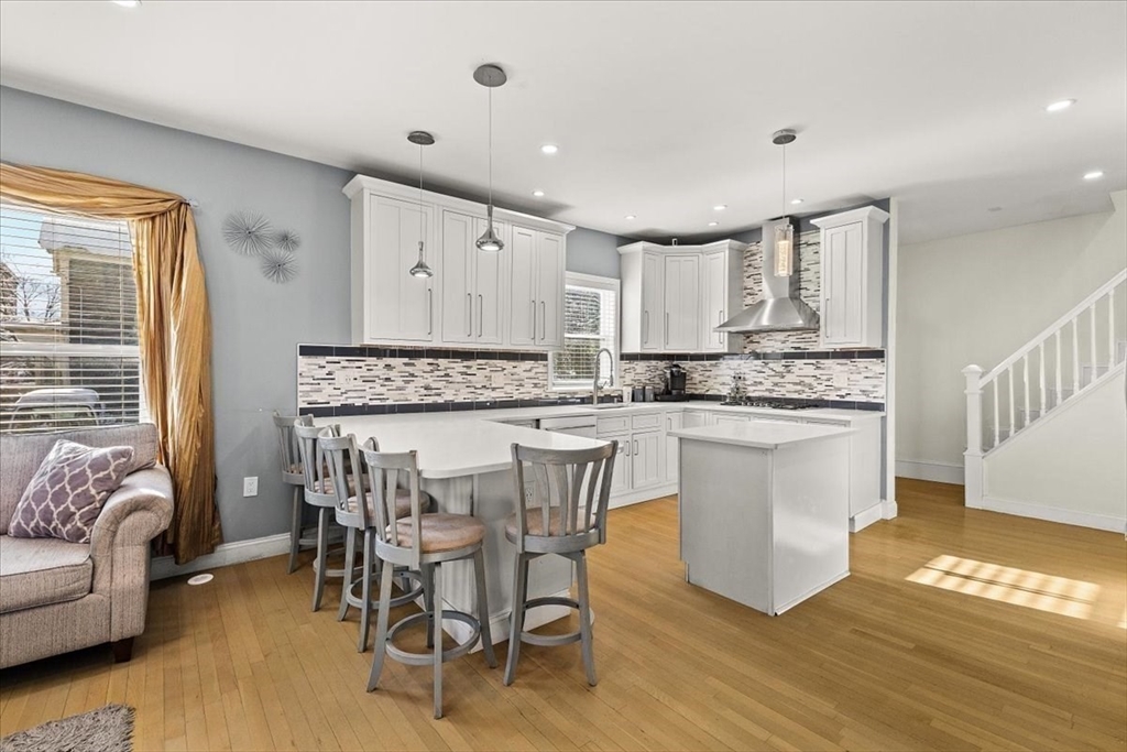 6 Arion Street Boston, MA 02125 - Photo 4 of 42 a kitchen with kitchen island granite countertop wooden floors and white stainless steel appliances