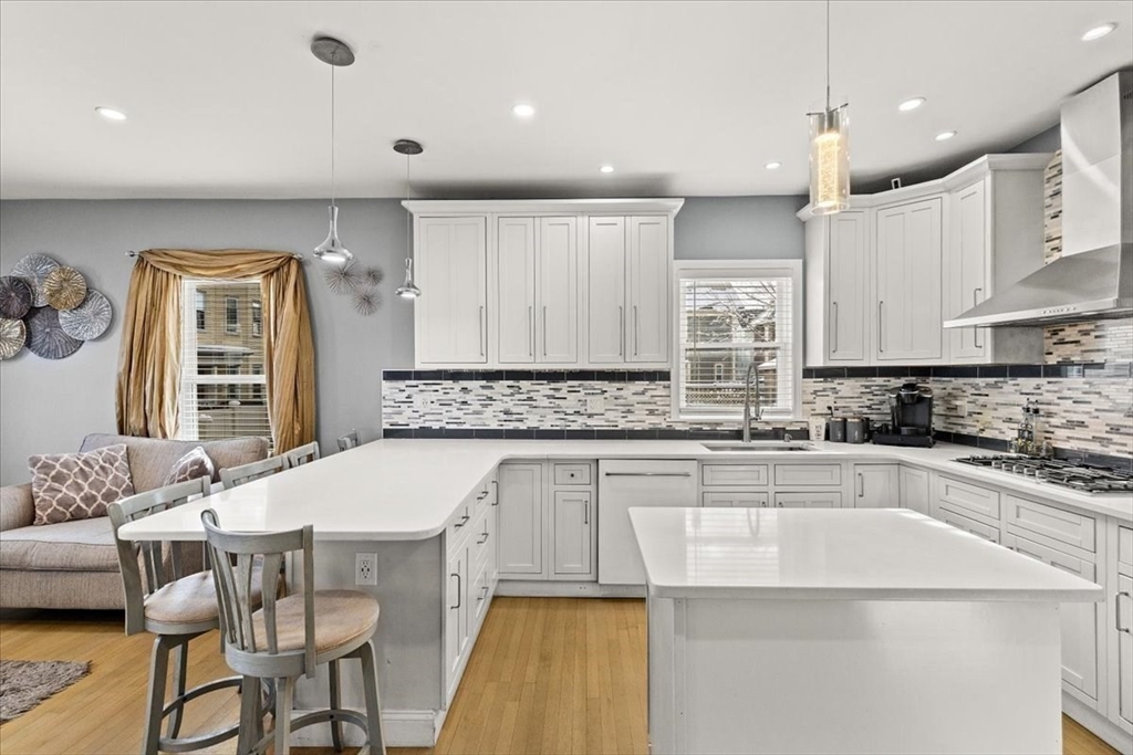 6 Arion Street Boston, MA 02125 - Photo 5 of 42 a kitchen with stainless steel appliances granite countertop a kitchen island a stove a sink a dining table and chairs with wooden floor