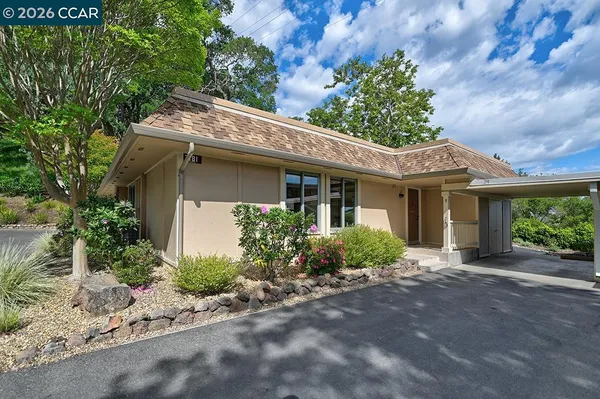 a front view of a house with a garden and tree