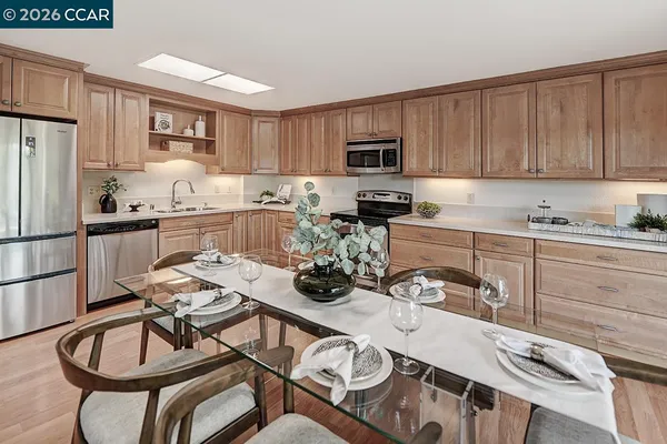 a kitchen with stainless steel appliances a white table and chairs in it