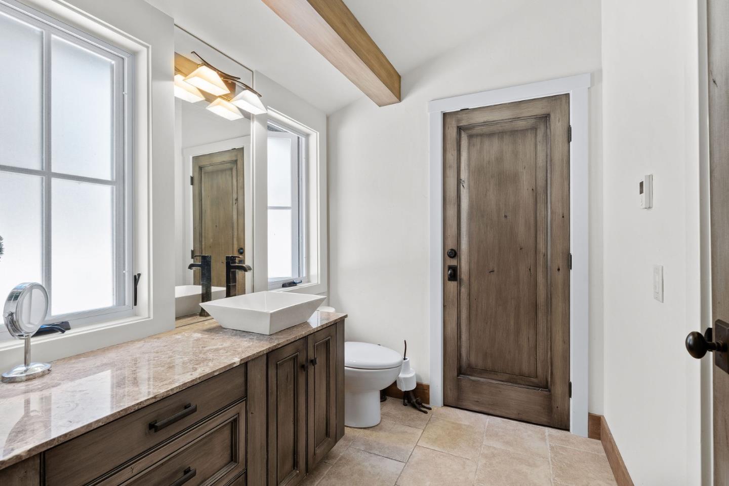 11627 Hidden Hills Road Carmel Valley, CA 93924 - Photo 32 of 62 a spacious bathroom with a granite countertop sink a toilet a mirror and a shower