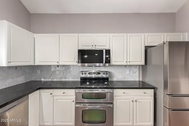 a kitchen with white cabinets and stainless steel appliances