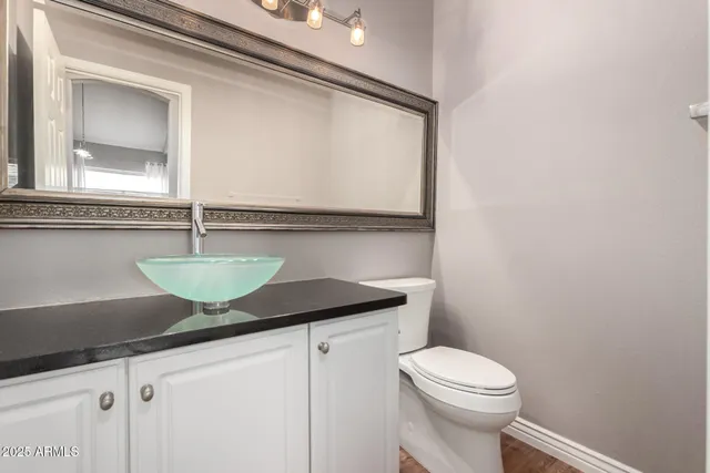 a bathroom with a granite countertop sink a toilet and a mirror