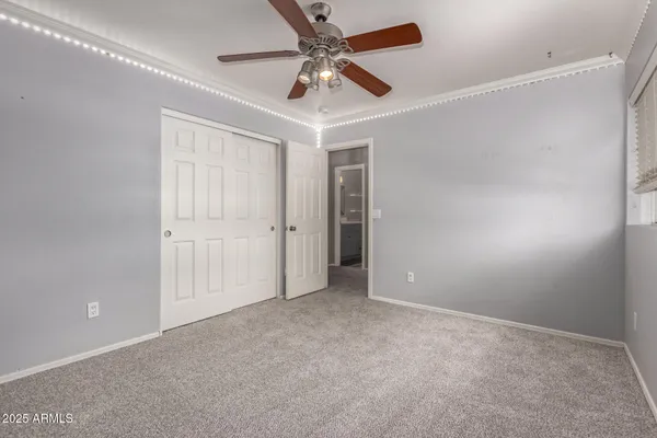 an empty room with a chandelier fan and windows