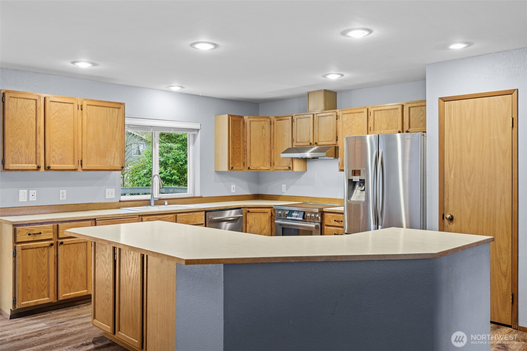 21641 Southeast 266th Street Maple Valley, WA 98038 - Photo 11 of 40 a kitchen with stainless steel appliances granite countertop a sink a stove a refrigerator a center island and a window