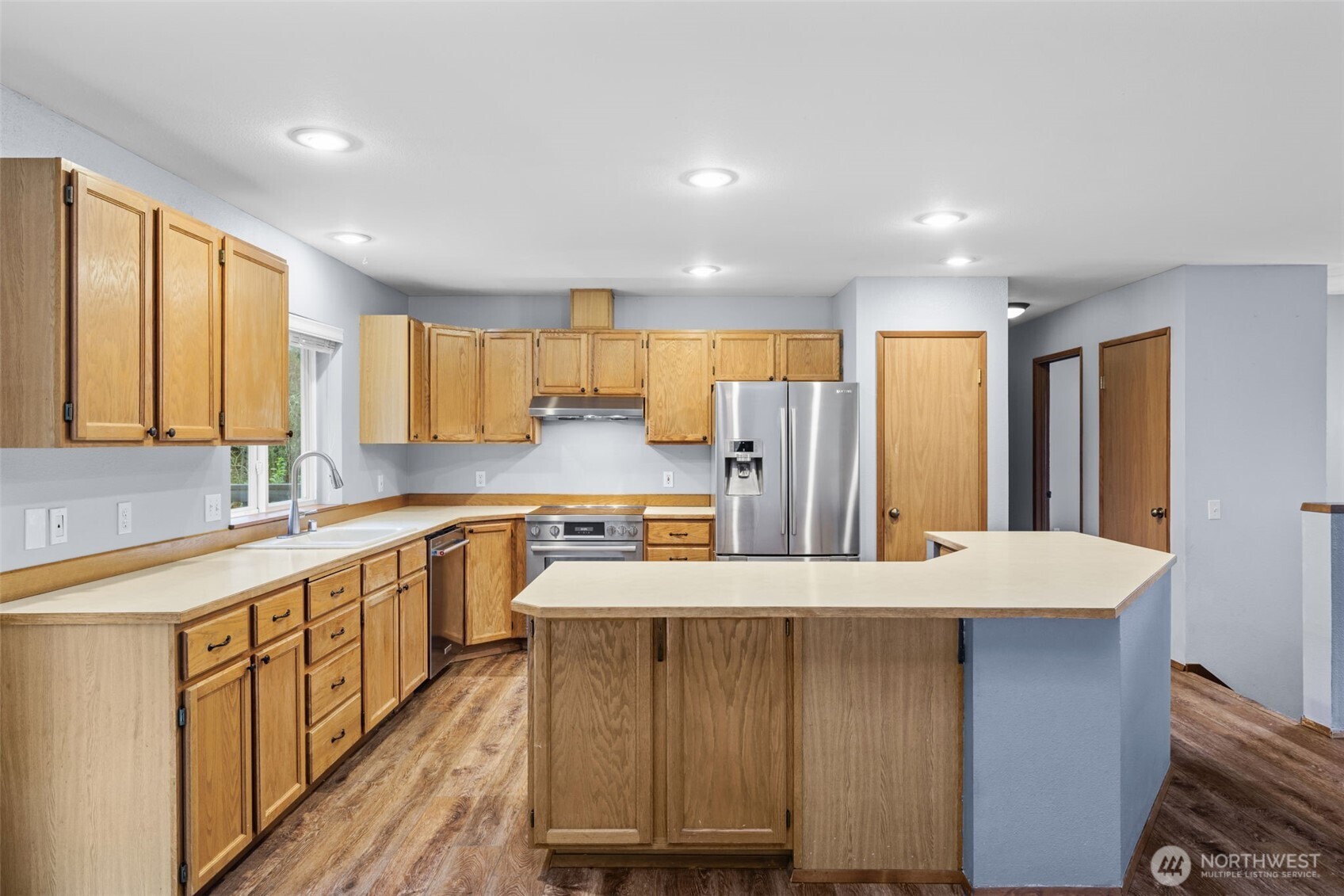 21641 Southeast 266th Street Maple Valley, WA 98038 - Photo 10 of 40 a large kitchen with stainless steel appliances a large counter top a sink a refrigerator and a window
