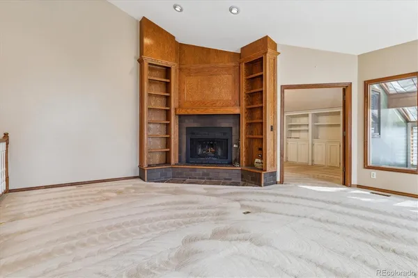 a view of an empty room with wooden floor and a fireplace