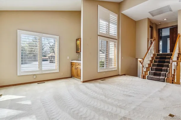 a view of an empty room with stairs and a window