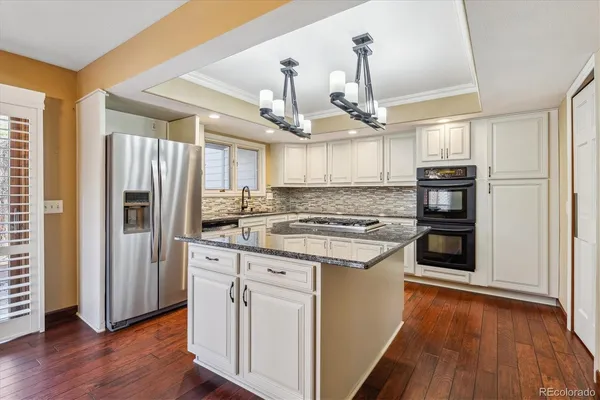 a kitchen with stainless steel appliances granite countertop a refrigerator a stove and a wooden floors