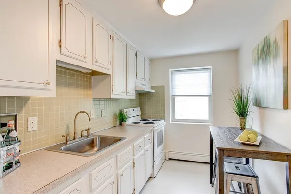 a kitchen with stainless steel appliances granite countertop a sink a window and white cabinets