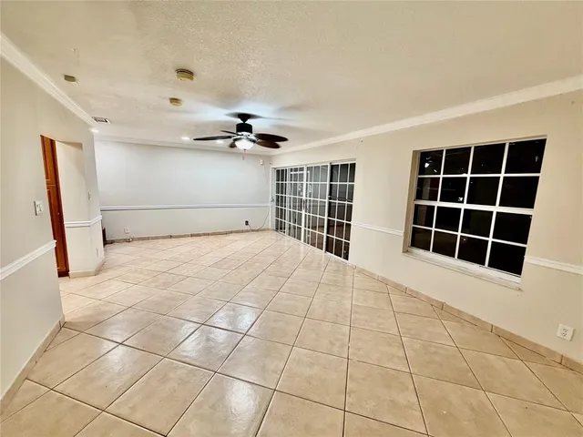 a view of an empty room with chandelier fan