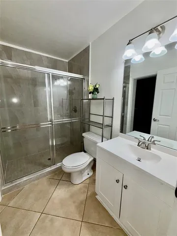 a view of an empty room with wooden floor and fan