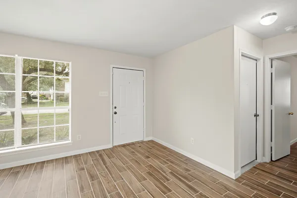 an empty room with wooden floor and windows
