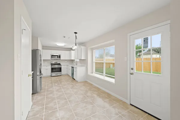 a large white kitchen with window and refrigerator