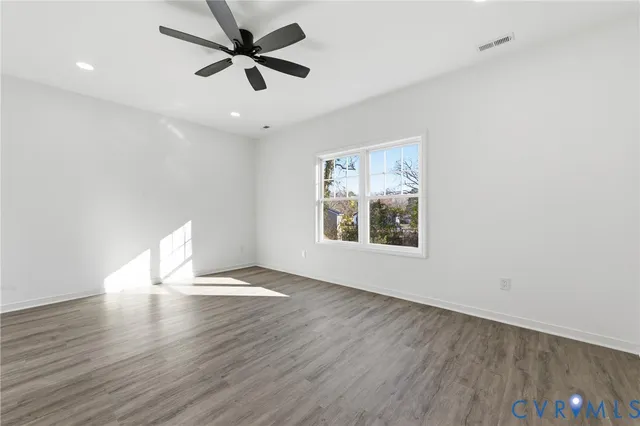 an empty room with wooden floor and a ceiling fan