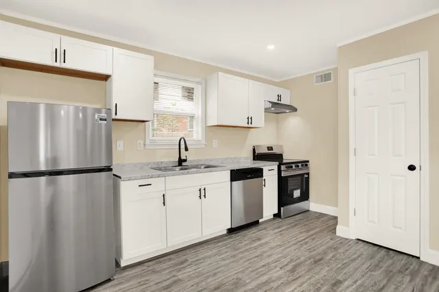 a kitchen with granite countertop a refrigerator sink and cabinets