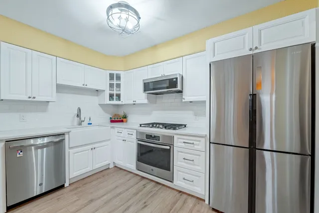 a kitchen with stainless steel appliances a stove a refrigerator and white cabinets