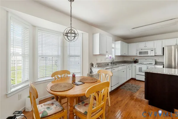 a kitchen with stainless steel appliances kitchen island granite countertop a sink a stove a dining table and chairs