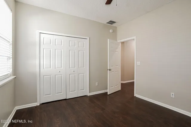 an empty room with wooden floor & closet area