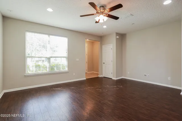 an empty room with wooden floor fan and windows