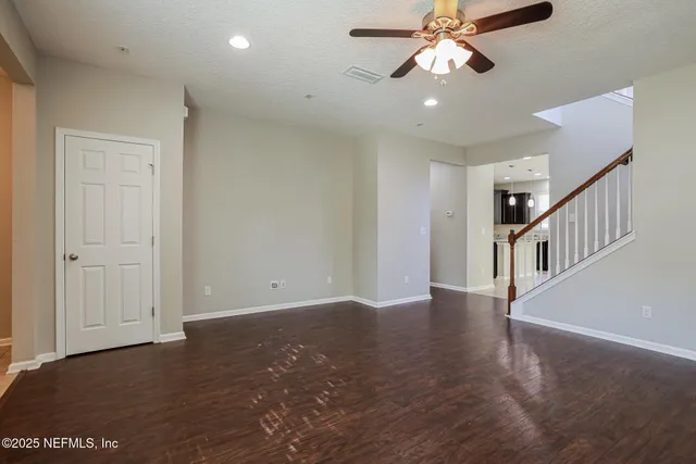 a view of an empty room with chandelier fan and wooden floor