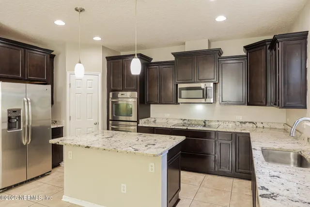a kitchen with stainless steel appliances kitchen island granite countertop a sink and a refrigerator