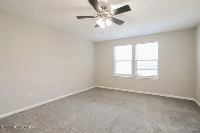 an empty room with a window and a fan