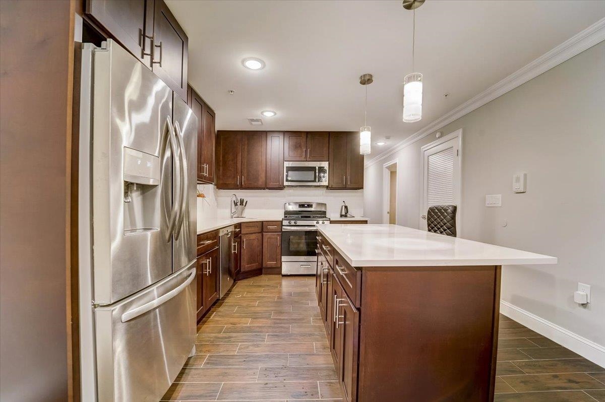 2765 John F. Kennedy Boulevard, Unit 1 Jersey City, NJ 07306 - Photo 12 of 33 a kitchen with stainless steel appliances granite countertop a refrigerator a sink dishwasher a stove oven and white countertops with wooden floor