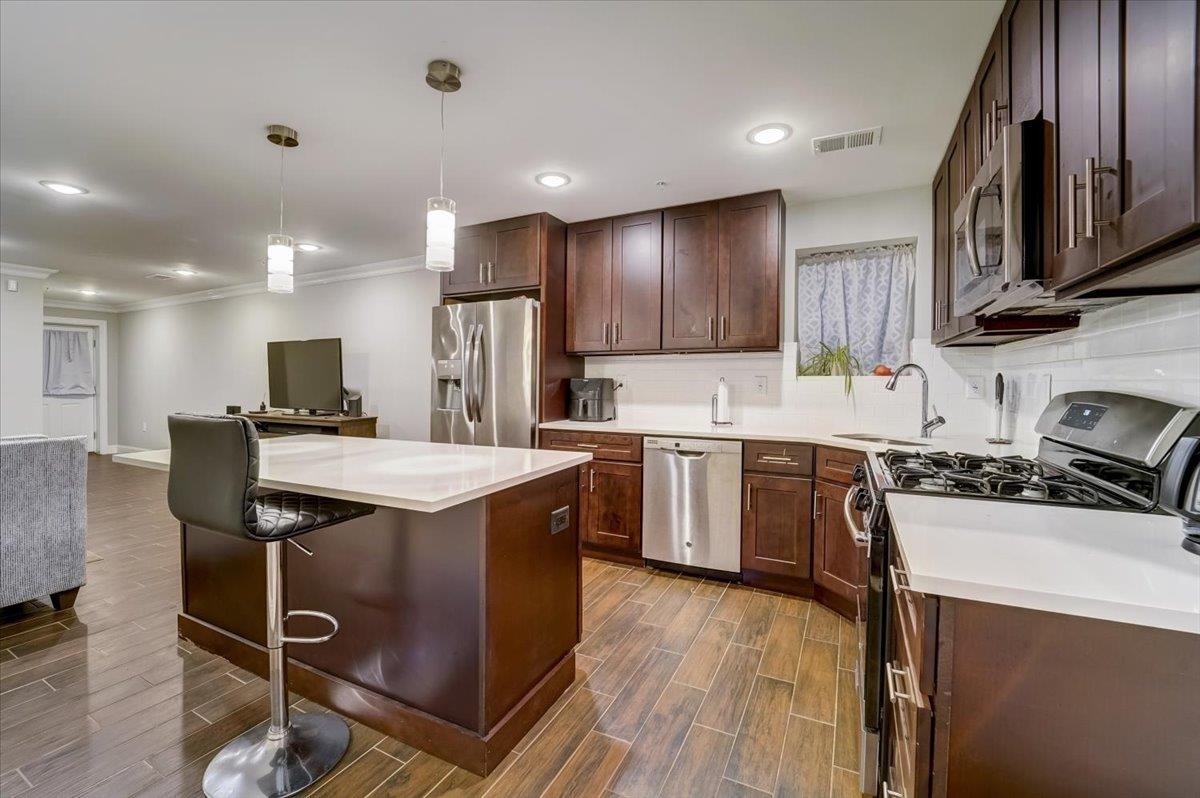 2765 John F. Kennedy Boulevard, Unit 1 Jersey City, NJ 07306 - Photo 14 of 33 a kitchen with kitchen island stainless steel appliances a sink a stove a refrigerator cabinets and a dining table