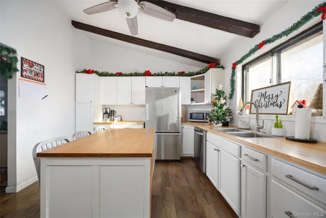 a kitchen with a sink dishwasher a stove and white cabinets with wooden floor