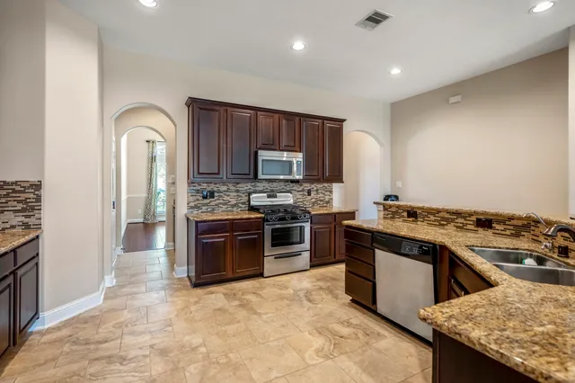 a kitchen with stainless steel appliances granite countertop a stove top oven a sink and dishwasher