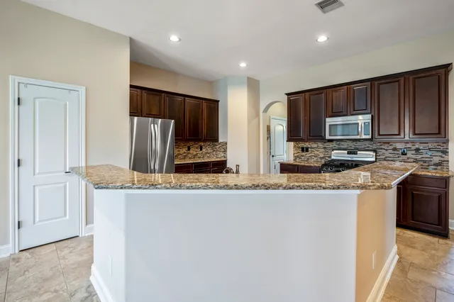 a kitchen with stainless steel appliances granite countertop a refrigerator a stove top oven a sink and dishwasher